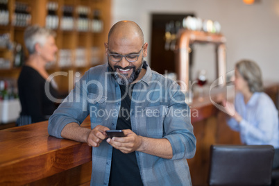 Man using mobile phone at counter in bar