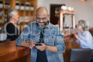 Man using mobile phone at counter in bar