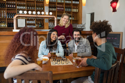 Friends interacting while having glass of beer