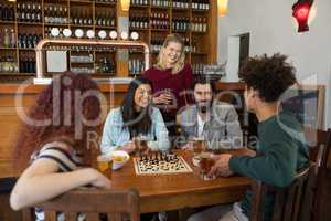 Friends interacting while having glass of beer