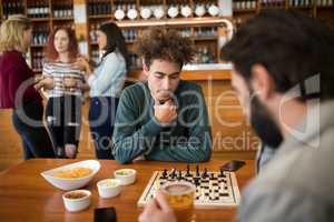Two men playing chess while having glass of beer