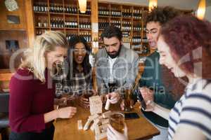 Friends playing with wooden blocks while having glass of beer