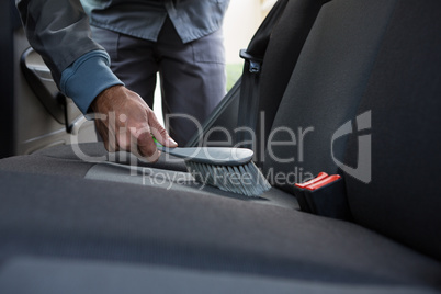 Male auto service staff cleaning a car with brush