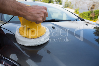 Auto service staff cleaning a car bonnet with rotating wash brush