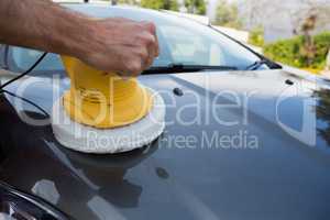 Auto service staff cleaning a car bonnet with rotating wash brush