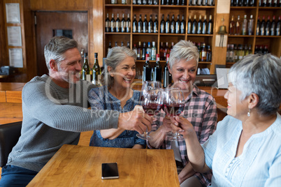 Group of smiling senior friends toasting glass of wine