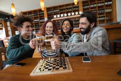 Friends toasting glass of beer in bar