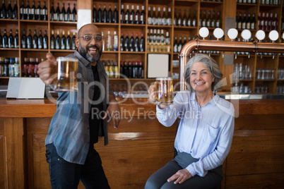 Two friends having glass of beer at counter in restaurant