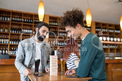 Two male friends looking at wooden blocks while having beer
