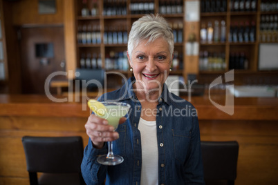 Senior woman having glass of cocktail in bar