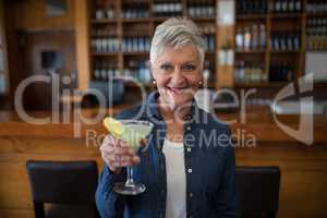 Senior woman having glass of cocktail in bar