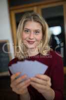 Beautiful woman holding cards in bar