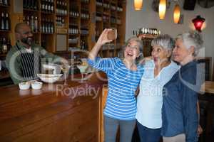 Senior friends taking selfie with mobile phone in bar