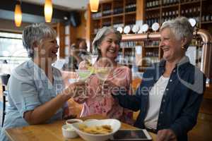 Senior female friends toasting glass of cocktail in bar
