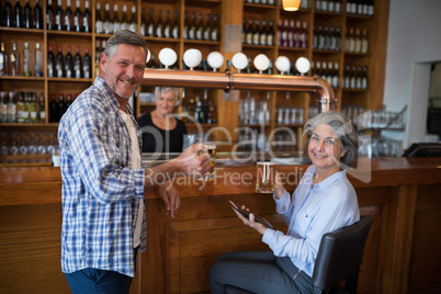 Two friends having glass of beer at counter in restaurant