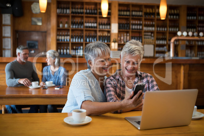 Smiling senior friends using mobile phone