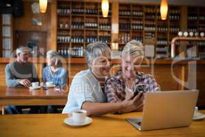 Smiling senior friends using mobile phone