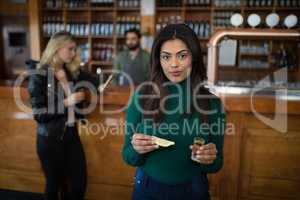 Beautiful woman holding tequila shot and lemon wedge in bar