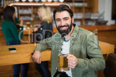 Happy man holding glass of beer in bar