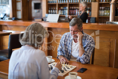 Friends playing chess while having coffee