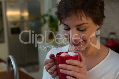 Woman having hot drink in kitchen