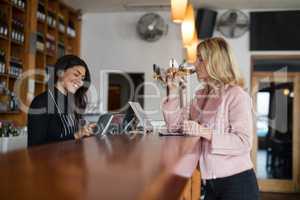 Waitress standing at counter while woman having glass of wine