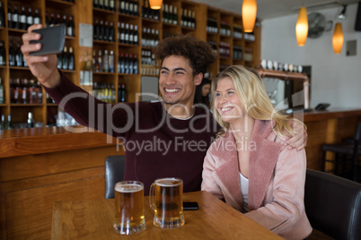 Couple taking selfie with mobile phone in bar