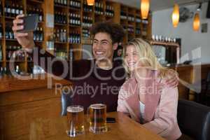 Couple taking selfie with mobile phone in bar