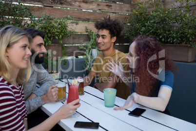 Friends interacting while having glass of drinks