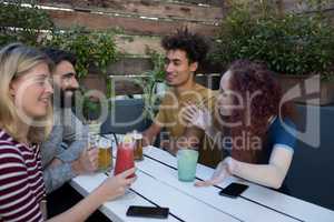 Friends interacting while having glass of drinks