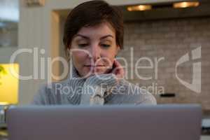 Woman using laptop in kitchen