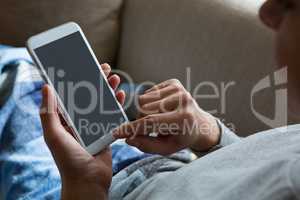 Woman using mobile phone on sofa in living room