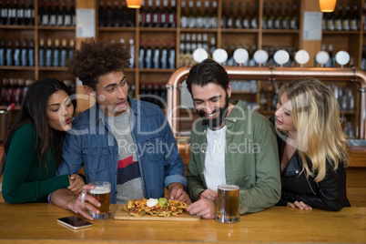 Group of friends having glass of beer and mexican food in bar