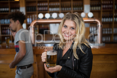 Beautiful woman holding glass of beer in bar