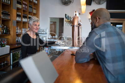 Man talking to senior waitress at counter