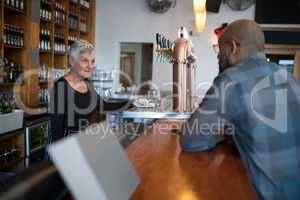 Man talking to senior waitress at counter