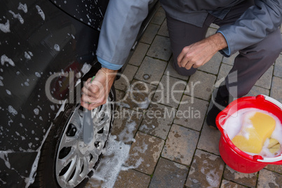 Auto service staff washing a tyre with brush