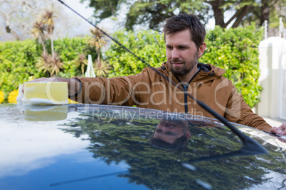 Auto service staff washing a car roof with sponge