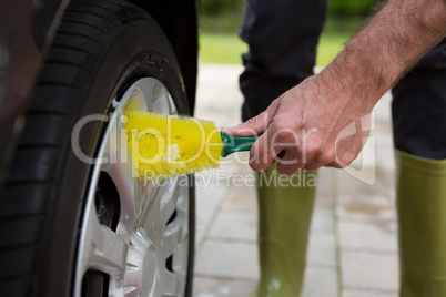 Auto service staff washing a tyre with brush