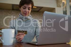 Woman doing online shopping with a credit card on laptop