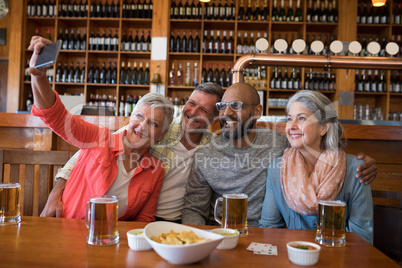 Friends taking selfie with mobile phone in bar