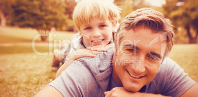 Father and son lying on field