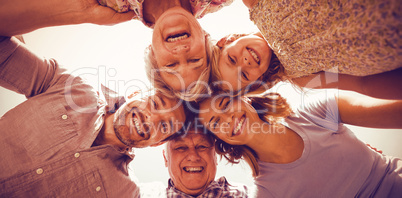 Happy family forming huddle against sky