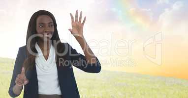 Businesswoman touching air in front of meadow clouds