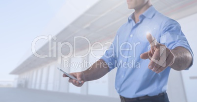 Businessman touching air with phone in front of warehouse