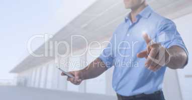 Businessman touching air with phone in front of warehouse