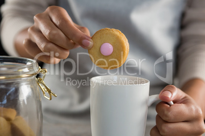 Woman dipping a cookie into a mug