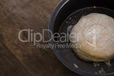 Kneaded dough placed in a bowl on a wooden table