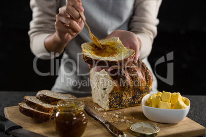 Woman applying jam over multigrain bread slice
