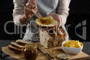 Woman applying jam over multigrain bread slice